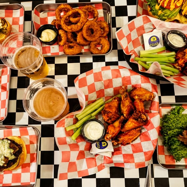 Delicious spread of burgers, hot dogs, fries, onion rings, and chicken wings with beer.